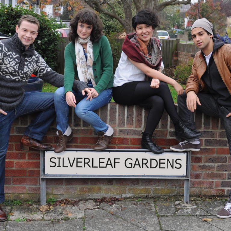 Vier junge Menschen sitzen auf einer Mauer über dem Schild "Silverleaf Gardens".