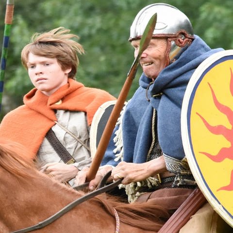 Ein keltisch gekleideter Mann und Junge reiten mit Schilden und Speren bewaffnet.