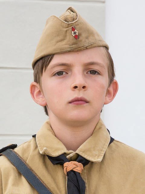 Portrait eines jungen in brauner Uniform mit Hakenkreuz-Abzeichen.