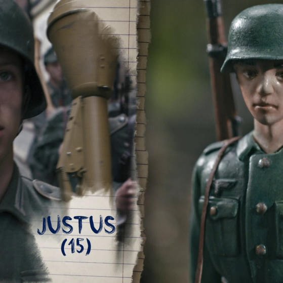 Justus mit Uniform, Helm und Waffe.