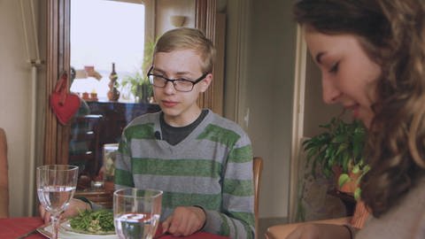 Ein Junge und eine junge Frau sitzen gemeinsam am Tisch und essen.