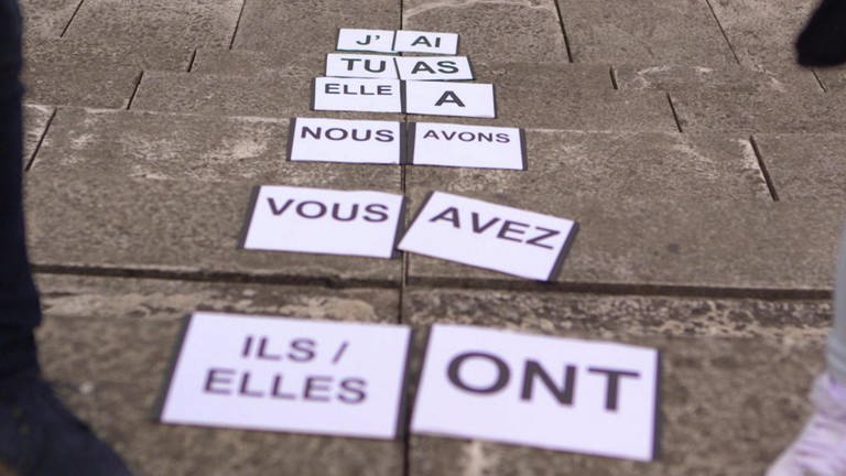 Auf dem Boden liegen Schilder, darauf stehen französische Pronomen und die Konjugationen von "avoir".