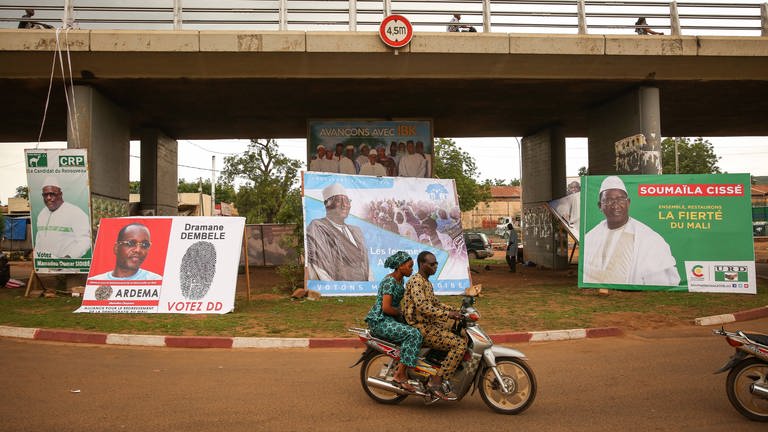 Wahlkampf in Mali für die Präsidentschaftswahl 2018 – ein junges Paar fährt auf einem Moped an Wahlplakaten vorbei