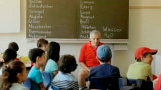 Ein Mann sitzt vor einer Klasse im Klassenzimmer.