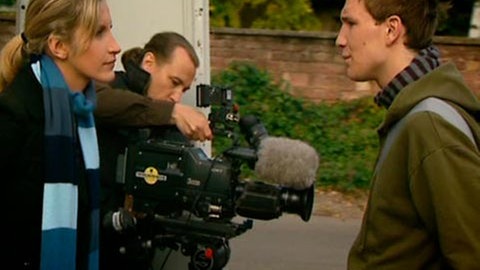 Hauptdarsteller Eugen (rechts) unterhält sich mit einer blonden Frau (links). Zwischen ihnen hantiert ein Mann an einer Fernsehkamera.