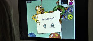 Auf einem Computerbildschirm sieht man eine Sequenz aus dem Lernspiel Deutsch lernen mit Mumbro und Zinell.