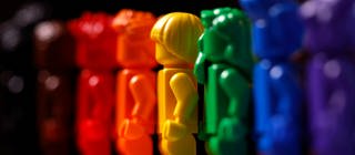 Plastikfiguren in den verschiedenen Farben des Regenbogens stehen nebeneinander