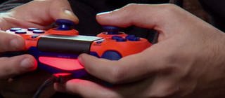 Aufnahme von Händen, die einen roten PS4 Controller halten.
