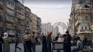 Menschen auf den Straßen einer zerstörten Stadt in Syrien - seit Jahren herrscht dort ein Bürgerkrieg. 