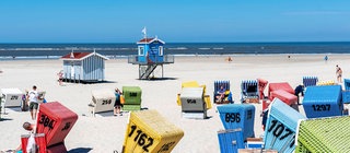 Ein Nordseestrand mit vielen bunten Strandkörben.