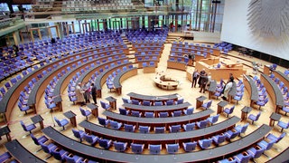 Der Plenarsaal im Deutschen Bundestag: Blaue Stühle im Kreis angeordnet.