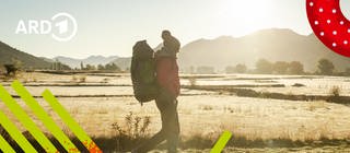 Ein Mensch wandert mit einem Rucksack bepackt durch die Landschaft