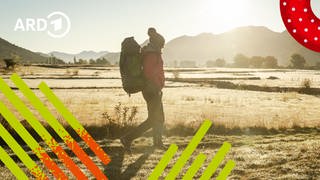 Ein Mensch wandert mit einem Rucksack bepackt durch die Landschaft