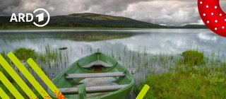 Ein Boot liegt am Ufer eines Sees mit ruhigem Wasser