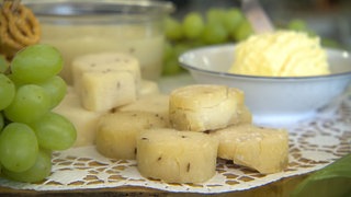 Kleine Handkäse mit Kümmel, drapiert auf einem Tisch mit Trauben