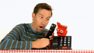 Ein Mann und eine rote Strumpfhandpuppe telefonieren.