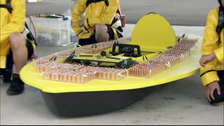 Ein gelbes, selbstgebautes Auto ist versehen mit vielen Batterien.