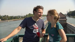 Ein Mann und eine Frau stehen auf einer Brücke und lachen miteinander. 