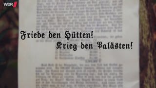 Eine verschwommene Fotografie eines Aufsatzes, davor schwebt der Schriftzug "Friede den Hütten! Krieg den Palästen!".