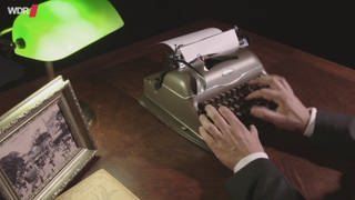 Hände tippen auf einer Schreibmaschine.