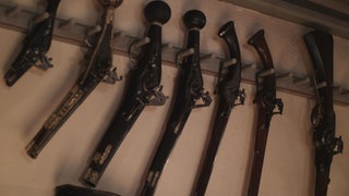 Historische Schusswaffen hängen an der Wand.