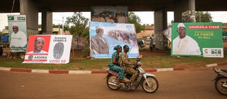 Wahlkampf in Mali für die Präsidentschaftswahl 2018 – ein junges Paar fährt auf einem Moped an Wahlplakaten vorbei