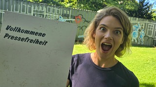 Host Lena Ganschow mit einem Demoplakat für Pressefreiheit