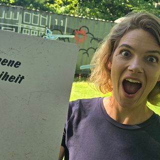 Host Lena Ganschow mit einem Demoplakat für Pressefreiheit